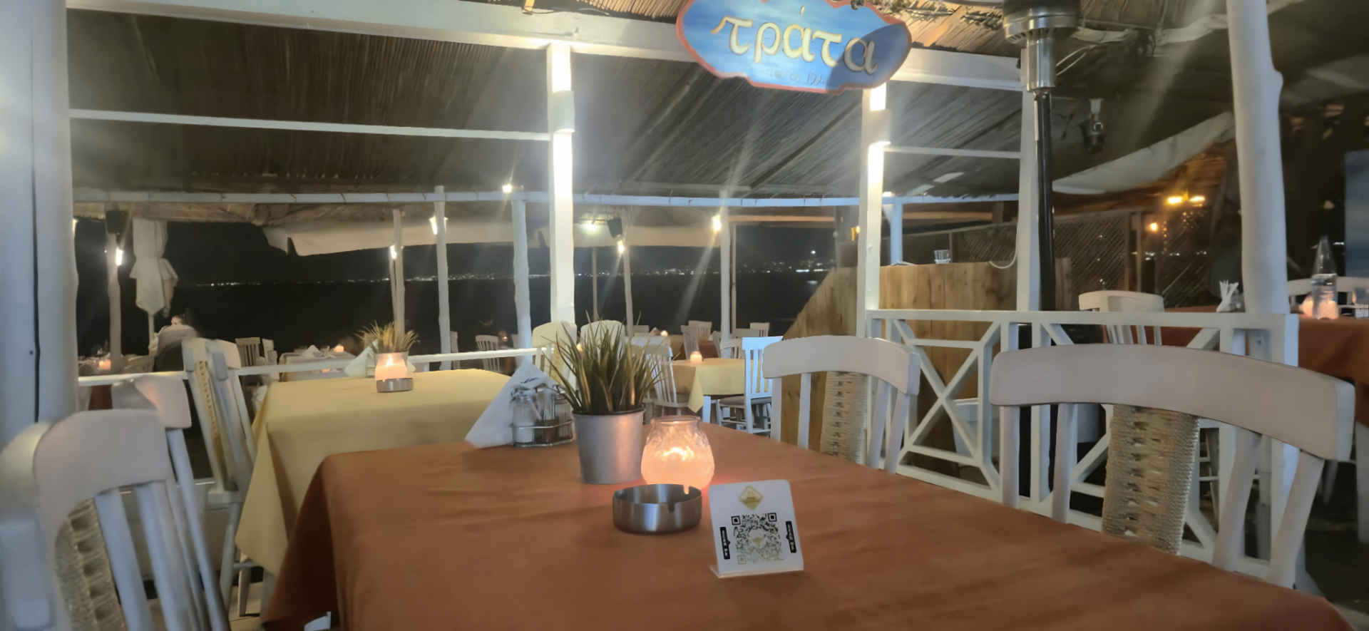 Seaside table at night under the Trata sign